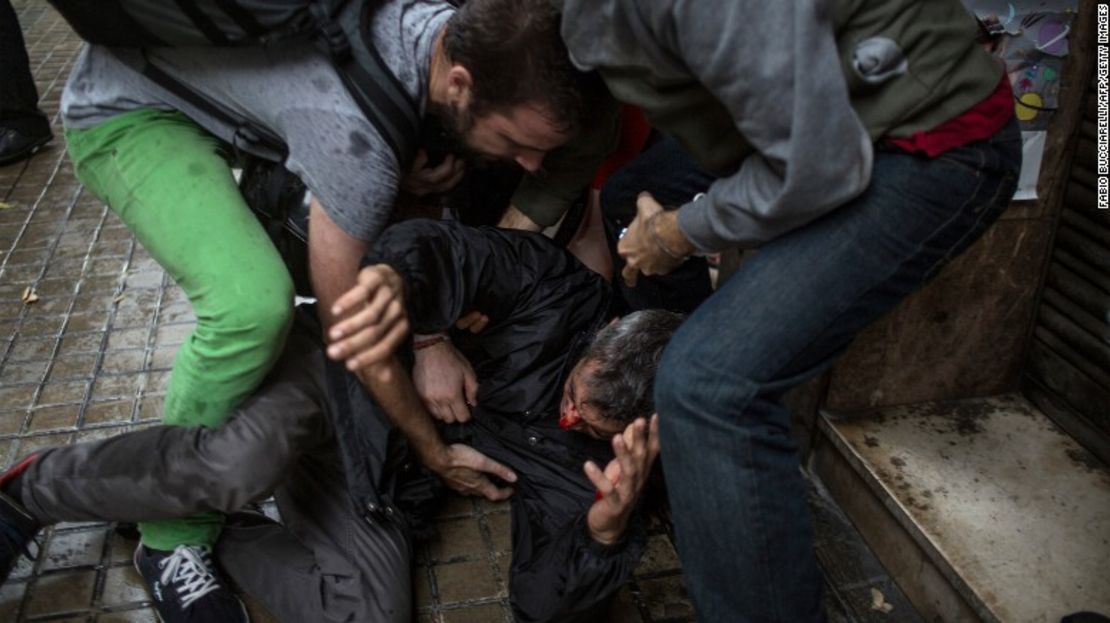 Personas ayudan a un hombre que quedó herido por una bala de goma disparada por la policía de España afuera de un centro de votación en Barcelona.