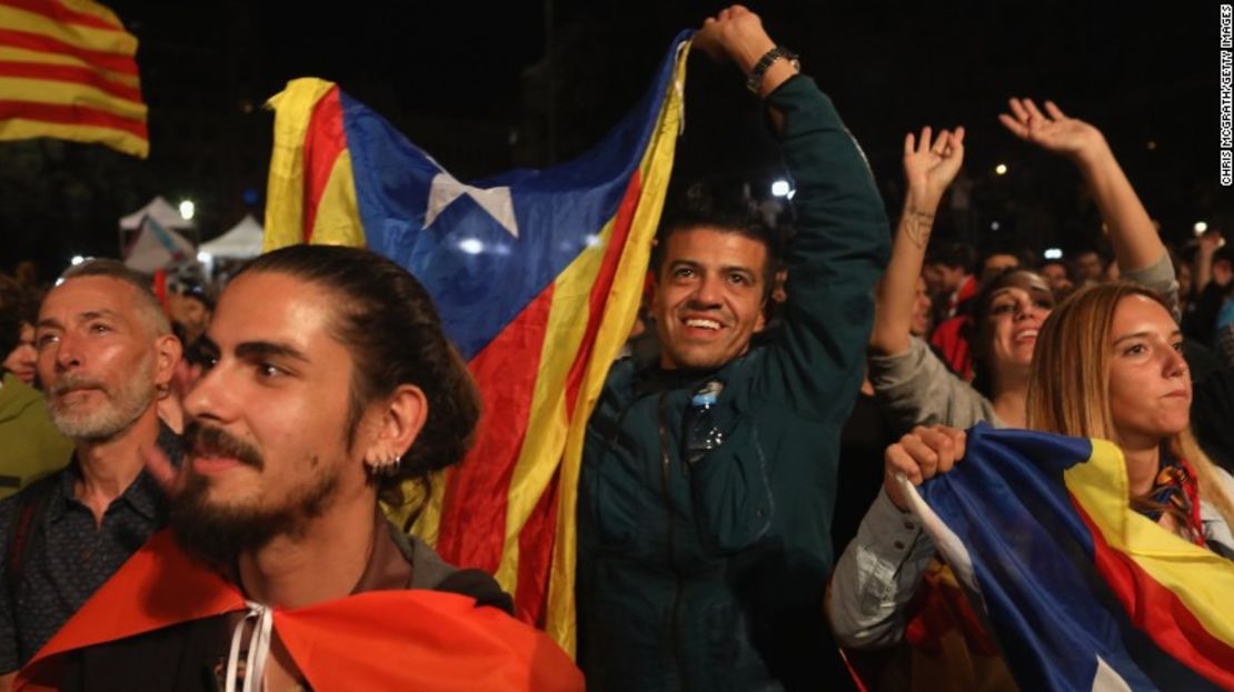 Algunas personas sostienen la bandera de Cataluña, mientras escuchan hablar al presidente de Cataluña Carles Puigdemont y esperan los resultados del referéndum.