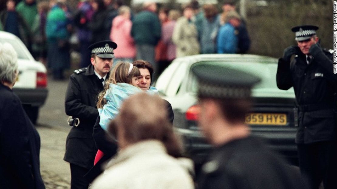 Una niña es retirada de la escuela primaria de Dunblane en Escocia, poco después del tiroteo de 1996.