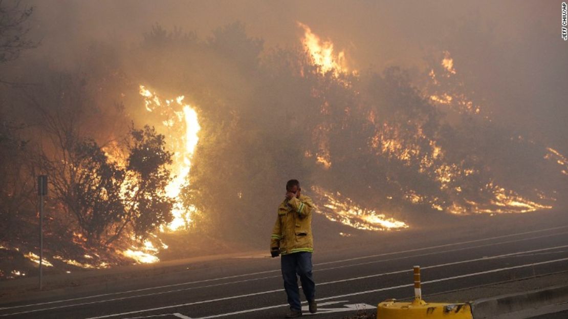 Un bombero cubre sus ojos mientras camina junto a una colina en llamas en Santa Rosa, California.