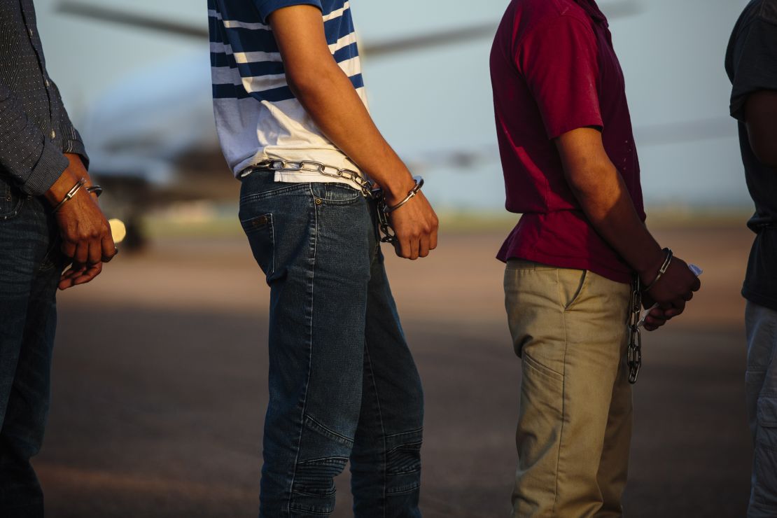 Los deportados esperan ser registrados por los guardias de inmigración antes de abordar el vuelo.