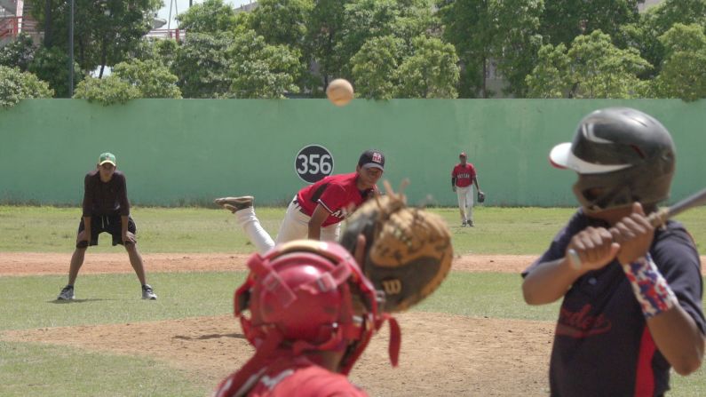 ¡Camará lenta resulta en una angustia intensa! Buscando quizás la imagen clásica de los pasatiempos en la República Dominicana, quisimos grabar a niños jugando béisbol y hacerlo estilizado, grabándolos en cámara lenta. Los hallamos jugando en el Centro Olímpico Juan Pablo Duarte. Fíjate detalladamente en la foto... Para obtener este ángulo se le ocurre a Asdrúbal ponerse detrás del catcher. Arriesgándose, sin pensar en que la pelota podría saltar del bate o escaparse del catcher como fuera, llegaría a romperle su cámara. Me llegó contando de su experiencia surreal pero no entendí muy bien la gravedad de la situación hasta que vi las tomas y, de acuerdo, ¡fue demasiado riesgoso! No creo que lo hagamos nuevamente, pero por su valentía, esa toma tiene mención aquí.