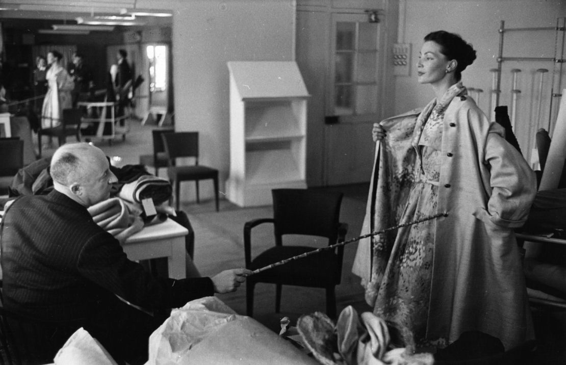 1952: Christian Dior inspecciona uno de sus diseños en su atelier en París.