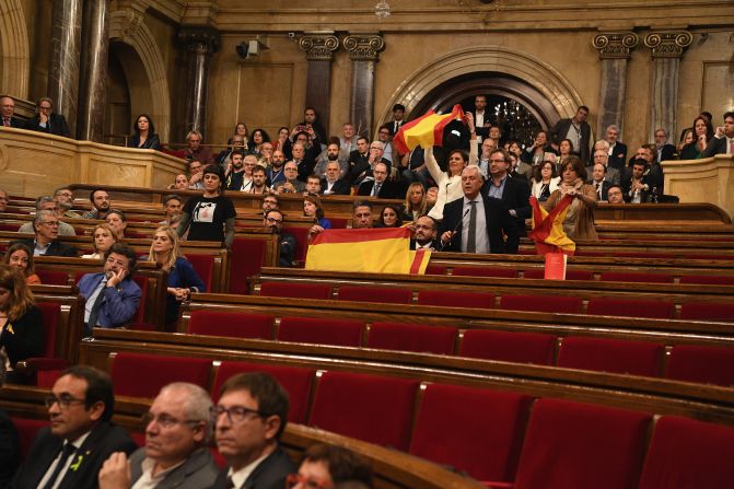 Miembros de partidos de la oposición ondean una bandera española antes de abandonar el Parlamento de Cataluña y antes de que se produjera la votación. El resultado fue de 70 votos a favor, 10 en contra y dos abstenciones.