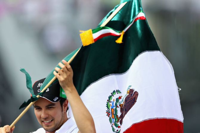 El piloto mexicano Sergio Pérez, de la escudería Force India, ondea la bandera de su país ante los espectadores.