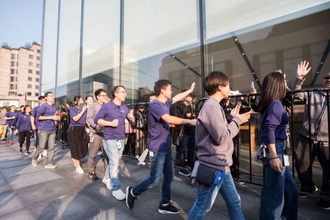 Empleados de Apple saludan a los clientes que hacen fila para comprar su iPhone X en China.