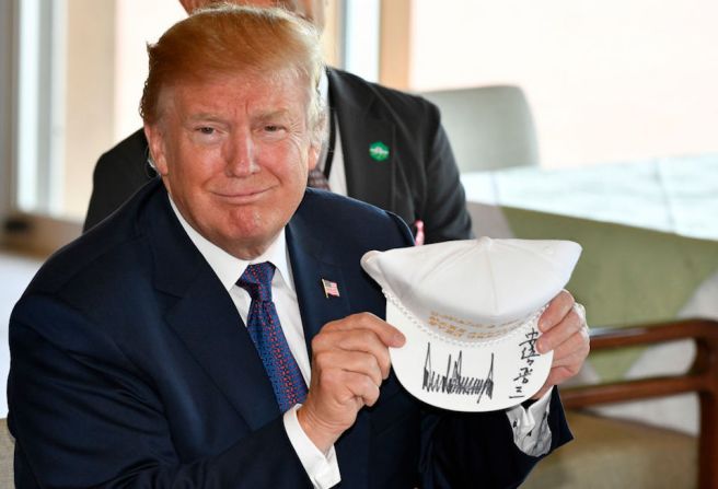 El presidente de Estados Unidos muestra a la cámara una de las gorras firmada por ambos mandatarios.