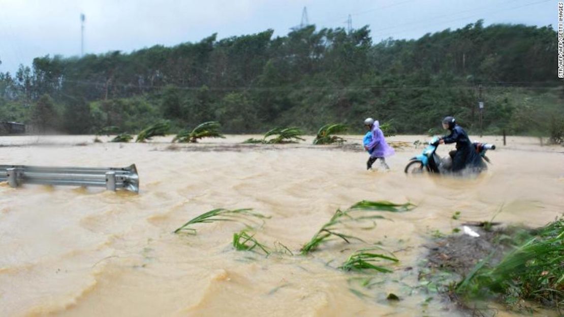 Dos personas caminan en medio de las inundaciones en una carretera en la provincia central de Dar Lak.