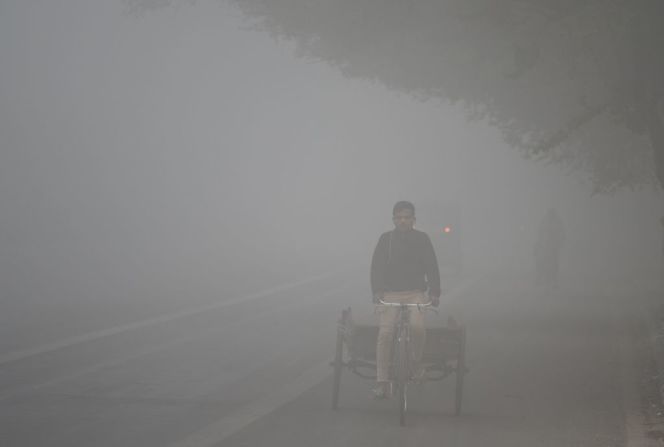 Un trabajador conduce por una calle con muy poca visibilidad por el smog.