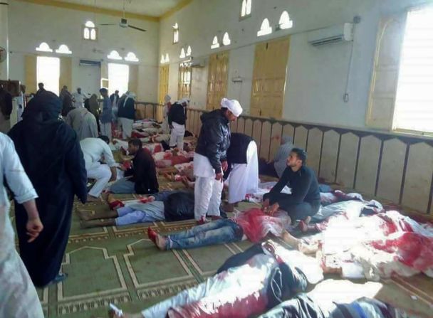 Egipcios caminan junto a los cuerpos de los fallecidos en el ataque a la mezquita.