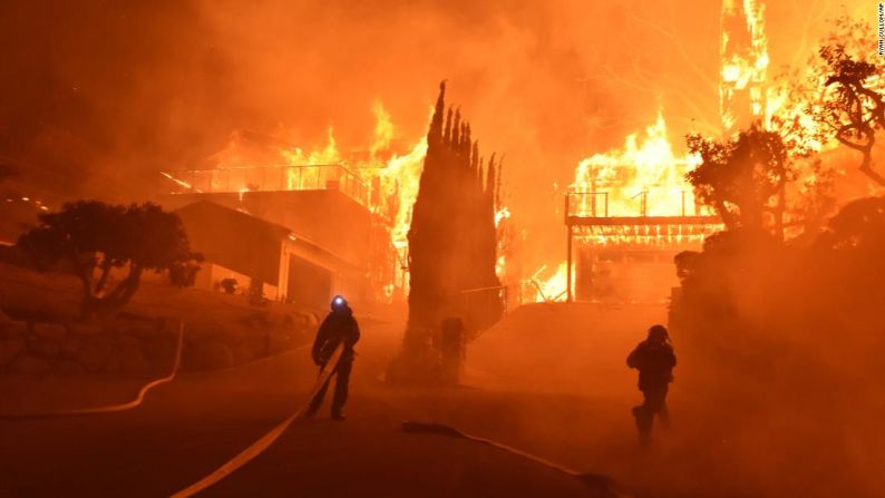 Los bomberos trabajan para apagar un incendio que envuelve hogares en Ventura. El fuego de rápido movimiento forzó a los ayudantes del sheriff a entrar a los vecindarios barrios y golpear las puertas de los hogares para advertirles a los residentes la necesidad de evacuar.