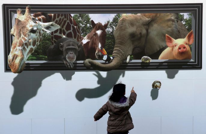 19 de febrero — una niña mira un dibujo 3D en el muro de seguridad de un sitio de construcción en Tokio.