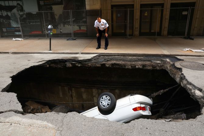 29 de junio — Un policía observa un gran forado en el que cayó un automóvil, en el centro de St. Louis. El vehículo fue retirado por una grúa.