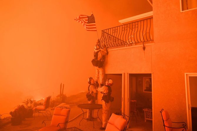 8 de julio — Un grupo de bomberos quitan una bandera de Estados Unidos de una casa en Oroville, California, durante uno de los incendios forestales que forzaron a miles de personas a evacuar sus hogares en el oeste de Estados Unidos.