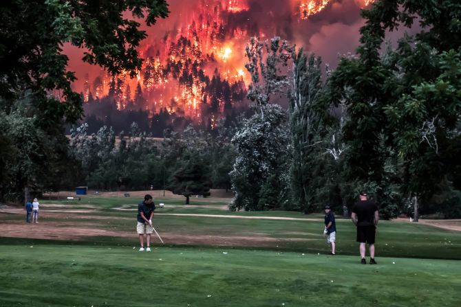 4 de septiembre — Golfistas juegan en North Bonneville, Washington, mientras el incendio forestal Eagle Creek arde cerca. El río Columbia proporcionó un amortiguador entre el incendio y el campo de golf Beacon Rock, según el gerente de operaciones del campo, Mark Mayfield.