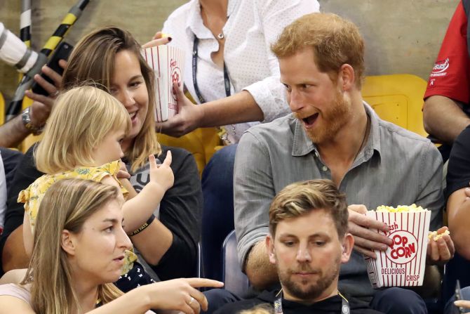 27 de septiembre — El príncipe Harry de Gran Bretaña se sienta con Hayley Henson, a la izquierda, y su hija Emily durante los Juegos Invictus en Toronto. Hayley está casada con el paralímpico británico David Henson, y la joven Emily estaba comiendo a escondidas las palomitas de maíz del príncipe.