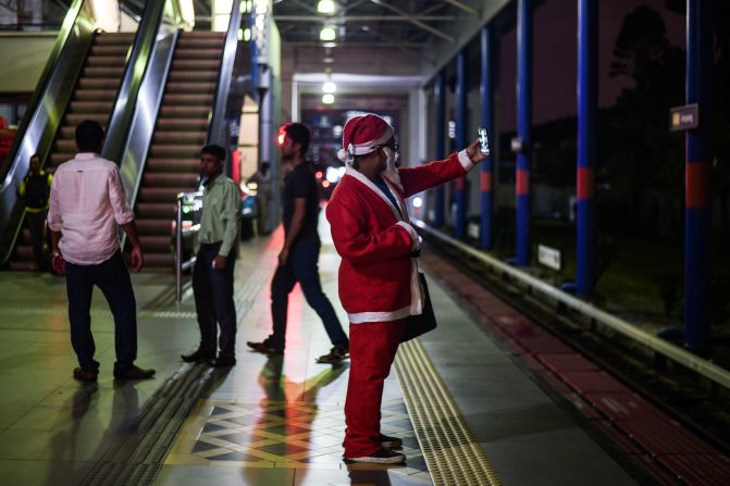 Malasia: un hombre vestido con un traje de Santa Claus se toma fotos mientras espera en una estación de tren en Kuala Lumpur.