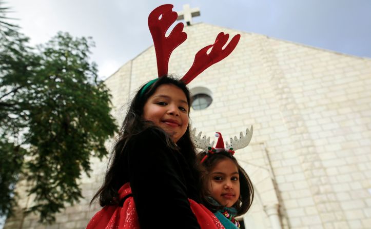 Palestina: niñas vistiendo cuernos de reno en la cabeza se paran frente a la Iglesia Católica Romana de la Sagrada Familia, en la ciudad de Gaza.