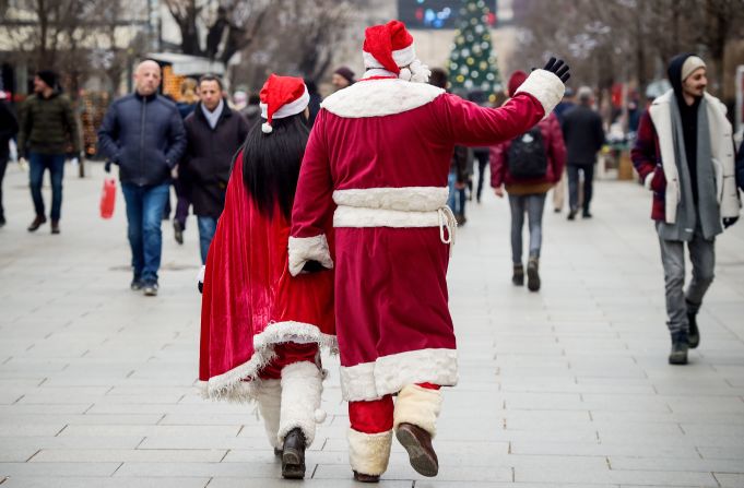 Kosovo: una pareja vestida con atuendos de Santa Claus camina por la plaza principal de Pristina.