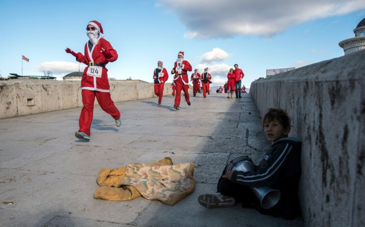 Macedonia: un niño toca la pandereta mientras hombres disfrazados de Papá Noel participan en la tradicional carrera de Año Nuevo de Santa Claus en Skopje.