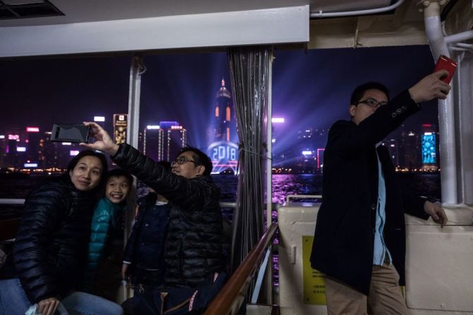 Paseantes se toman fotos a bordo de un ferry en el puerto de Victoria durante las celebraciones del año nuevo en Hong Kong.