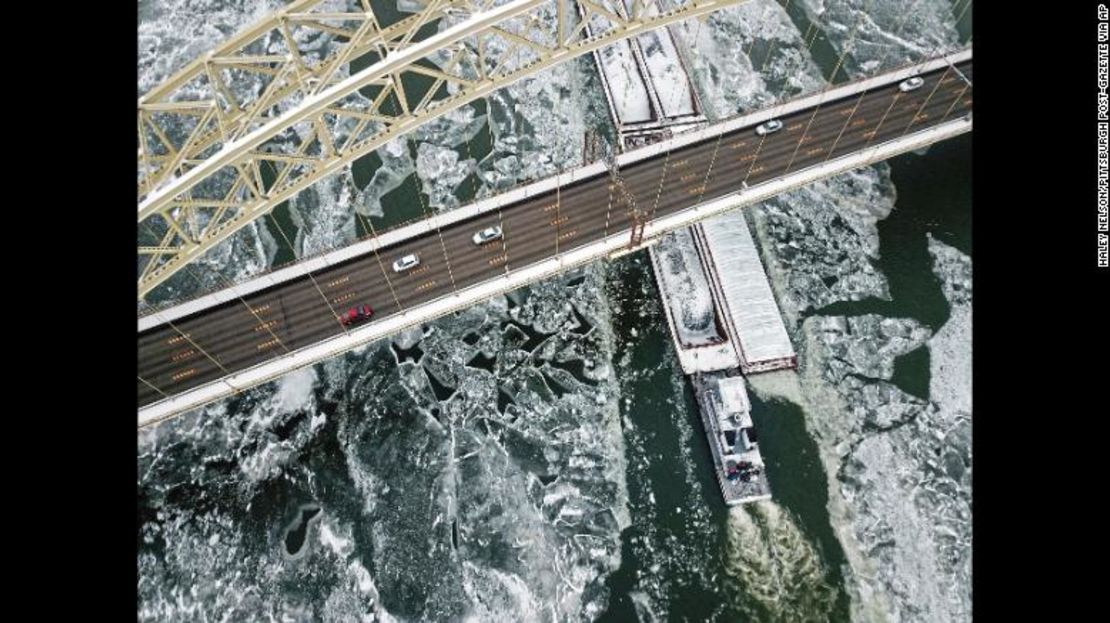 Una embarcación corta el hielo en el río Ohio, cuando pasa bajo el puente West End, a lo largo del distrito de North Shore en Pittsburgh.