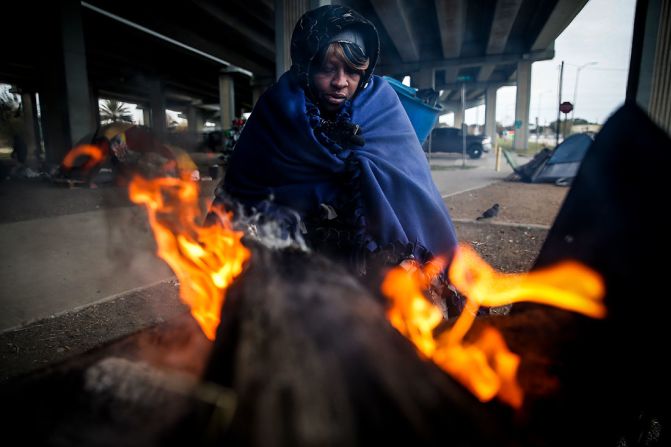 Tonya Sampson, una mujer sin hogar en Houston, intenta calentarse cerca a un fuego bajo la Autopista Eastex.