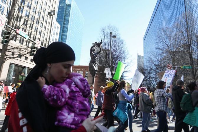 Participantes en la Marcha de las Mujeres en Charlotte, Carolina del Norte, pasan frente a una escultura de una madre y su hijo llamada "El Futuro".