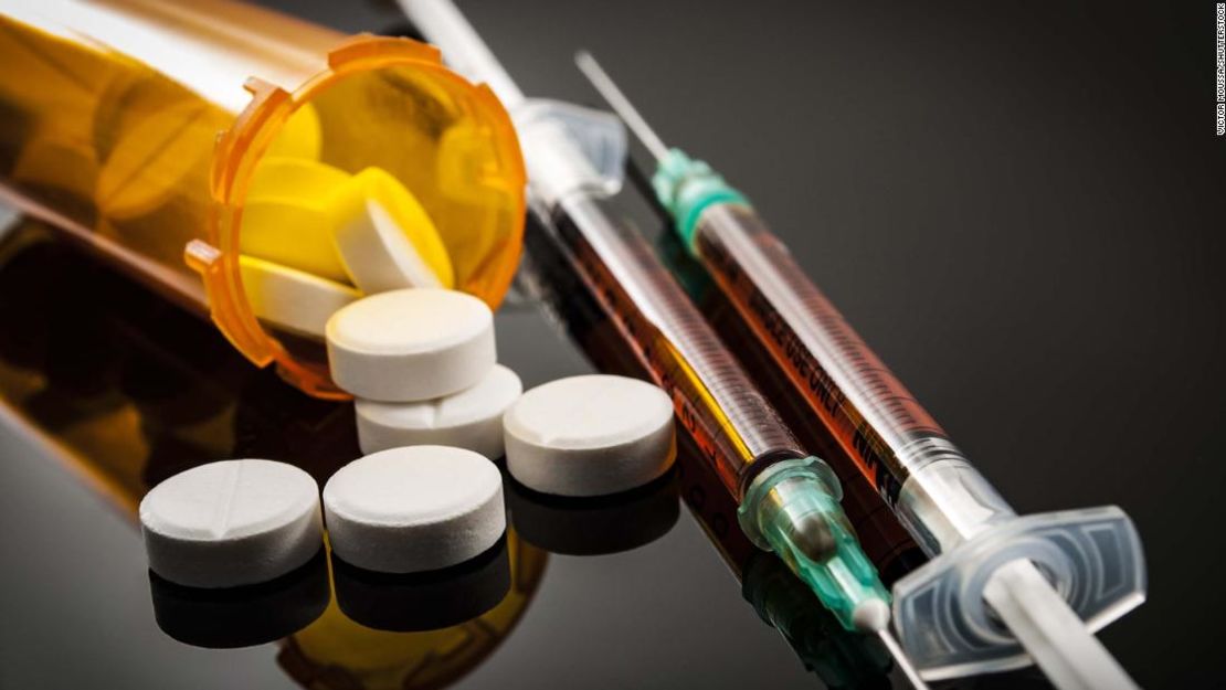 Opioid epidemic, drug abuse concept with closeup on two heroin syringes or other narcotics surrounded by scattered prescription opioids. Oxycodone is the generic name for a range of opioid painkillers; Shutterstock ID 706837198; Job: -