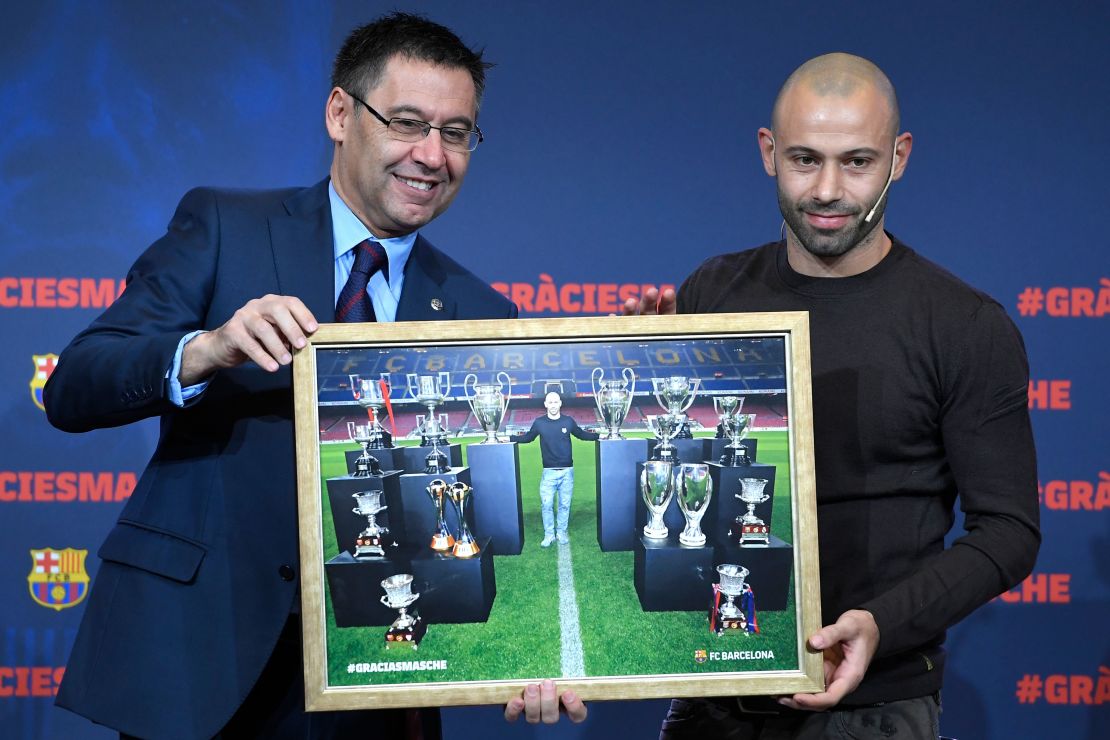 Josep Maria Bartomeu , presidente del FC Barcelona, y el defensa argentino Javier Mascherano posan con una foto enmarcada de Mascherano y los principales trofeos que ganó con el club de fútbol durante una ceremonia de despedida antes de su traspaso a China.