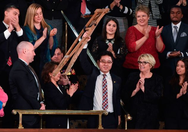 El desertor norcoreano Ji Seong-ho sostiene sus muletas en lo alto mientras es señalado por el presidente durante su discurso.