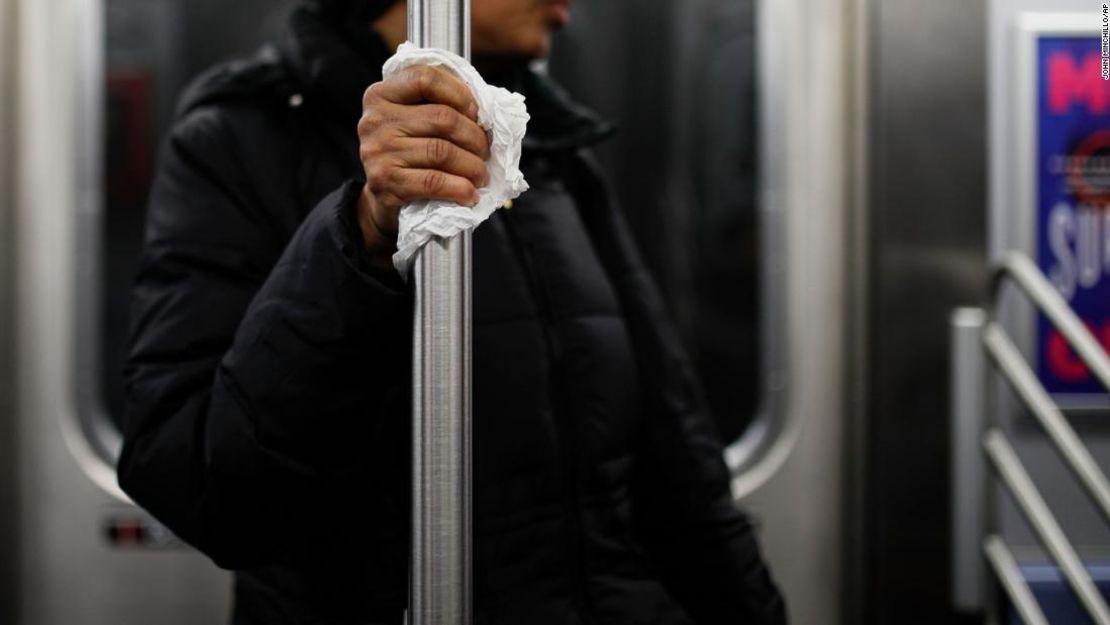 Una usuaria del metro de Nueva York usa un pañuelo para proteger su mano mientras se sostiene de un tubo el 19 de marzo.