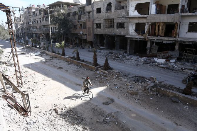 Un hombre monta en bicicleta en mitad de la destrucción en la ciudad de Hamouria, en Guta Oriental.