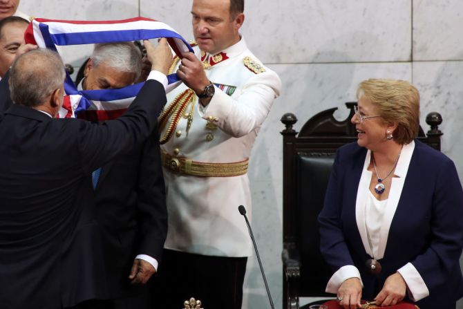 Sebastián Piñera recibe la cinta presidencial del presidente del Senado de Chile Carlos Montes mientras la saliente presidenta Michelle Bachelet observa.