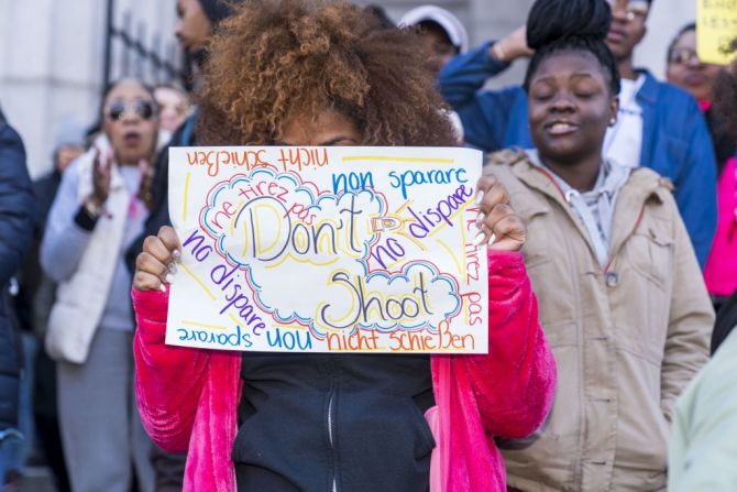 Una estudiante en Filadelfia esconde su rostro detrás de un letrero que dice "No disparen".