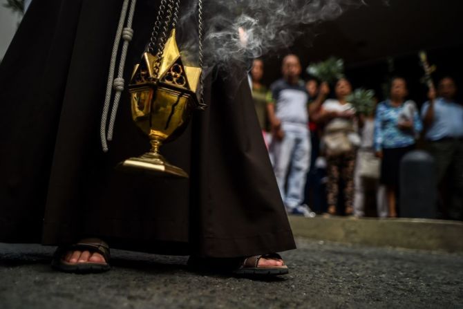 Un religioso sostiene un incensario en una iglesia de Cali, Colombia, durante la celebración del Domingo de Ramos en el inicio de la Semana Santa de 2018.