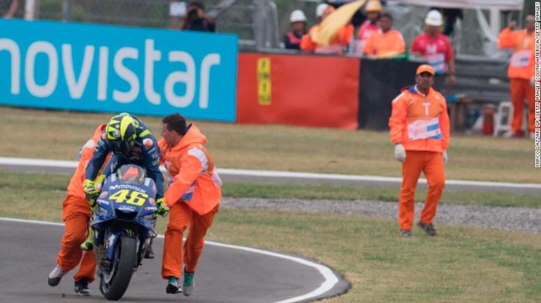 Valentino Rossi regresa, con ayuda, a su moto después de chocar.