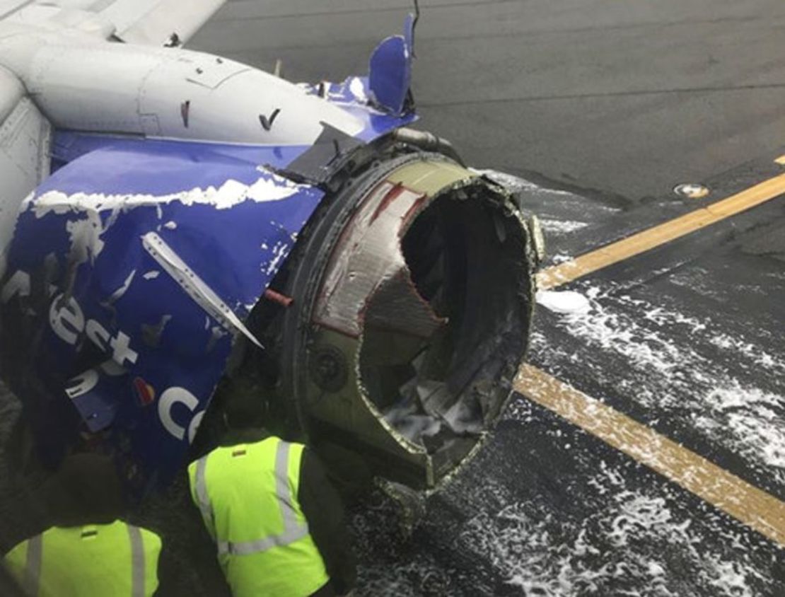 El motor del avión de Southwest Airlines es revisado mientras permanece en la pista del Aeropuerto Internacional de Filadelfia, tras el aterrizaje de emergencia.