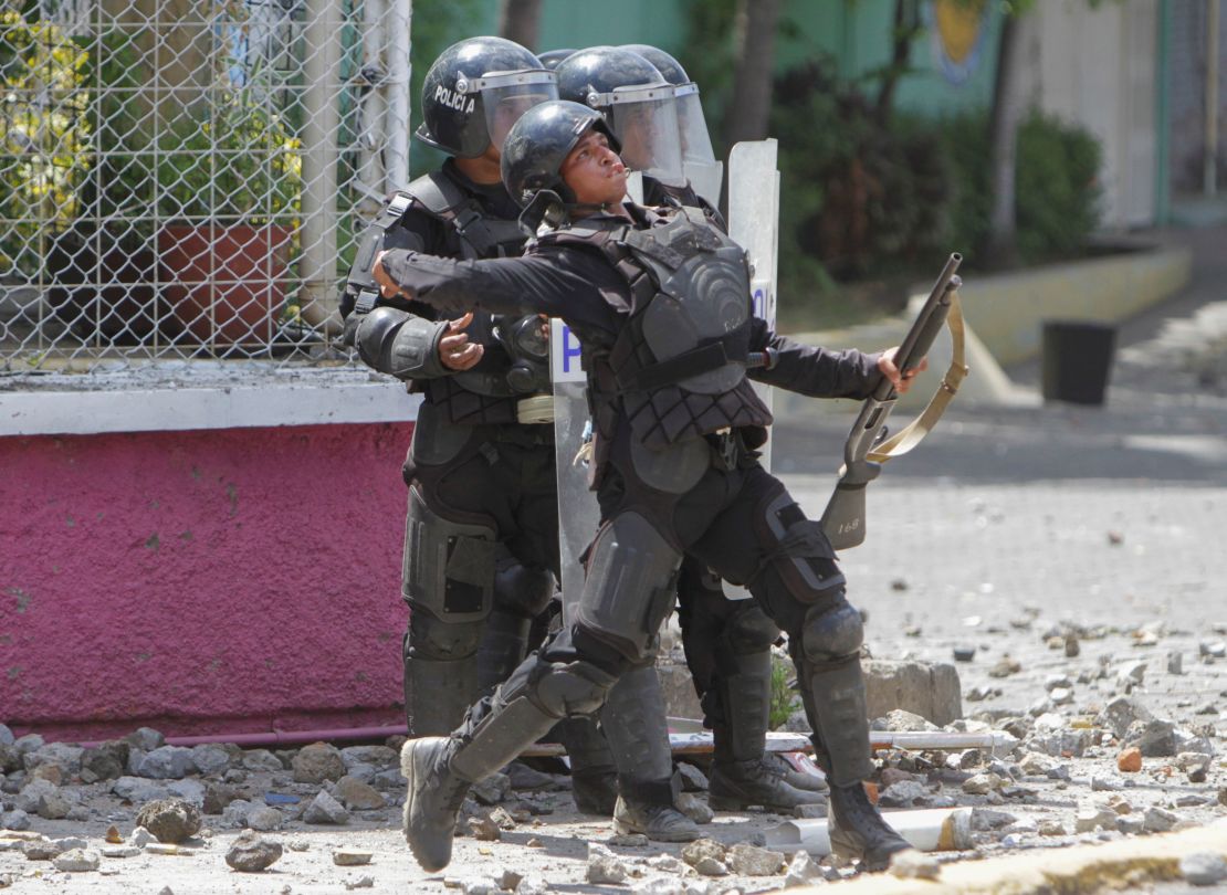 Un agente de policía tira una piedra a estudiantes frente a la Universidad Politécnica de Managua. Los universitarios protestan contra el cambio en el Seguro Social introducido por el gobierno. 19 de abril de 2018.