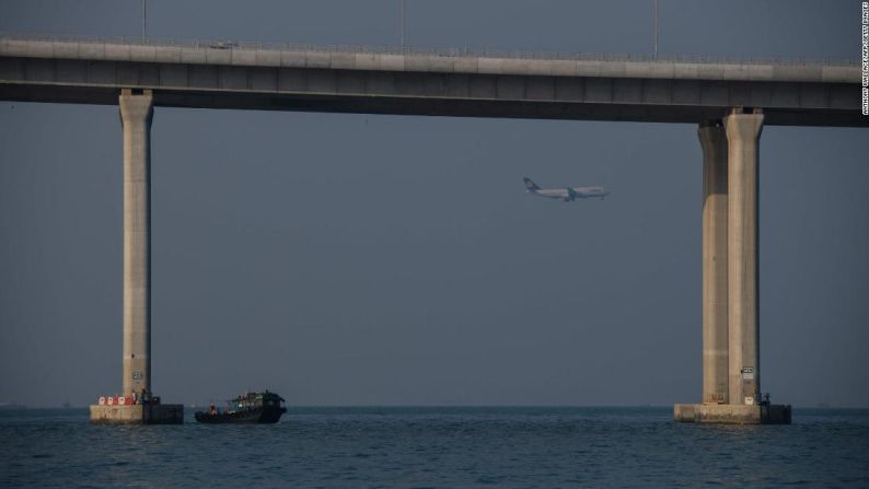 Un barco de transporte de trabajadores atraca junto a una columna del puente.