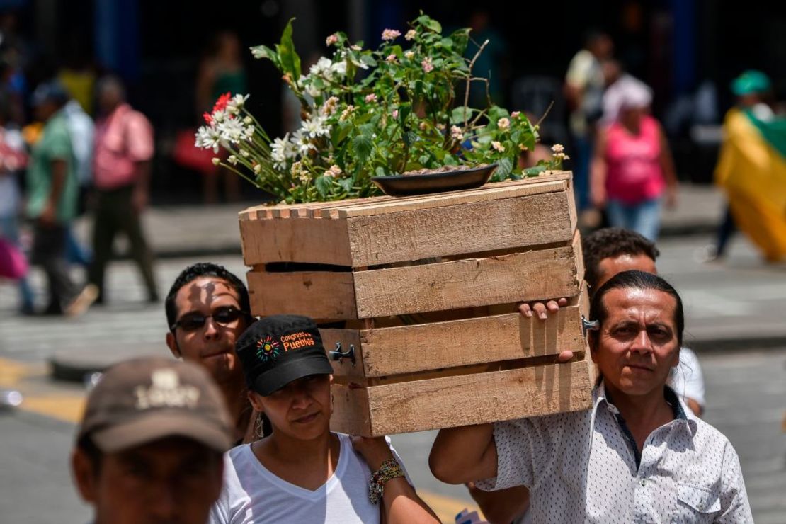 Un grupo de personas lleva un ataúd de madera que representa a las víctimas durante la conmemoración del Día Nacional de la Memoria y Solidaridad con las víctimas del conflicto armado, en Cali, Colombia, el 9 de abril de 2018.