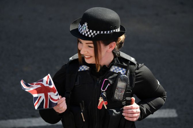 Una mujer policía con una bandera británica en los alrededores del castillo de Windsor.