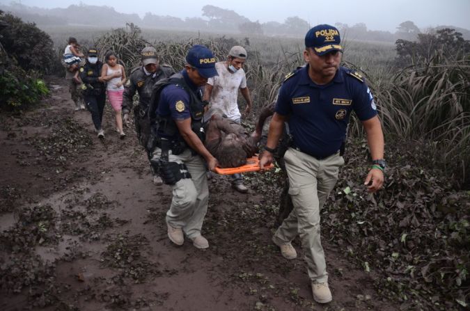 Agentes de policía cargan a un hombre herido en la erupción del Volcán de Fuego. Al menos 1,7 millones de personas en Guatemala están en riesgo por las cenizas, lava, gases tóxicos y posibles deslaves.