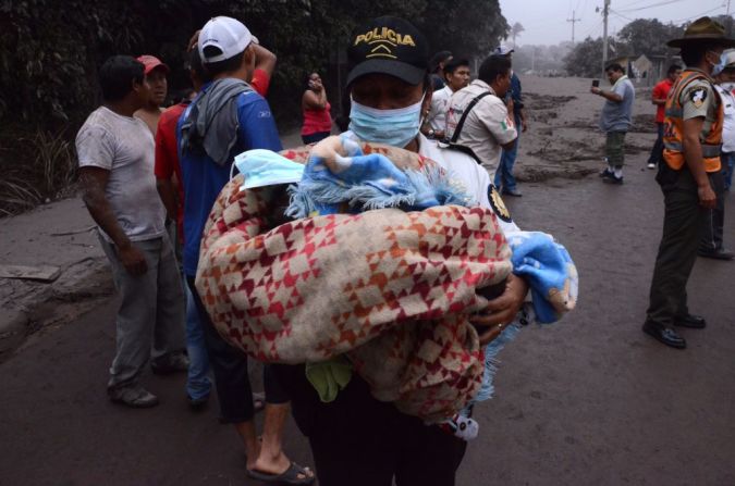 Un policía lleva en sus brazos a un bebé rescatado tras la erupción.