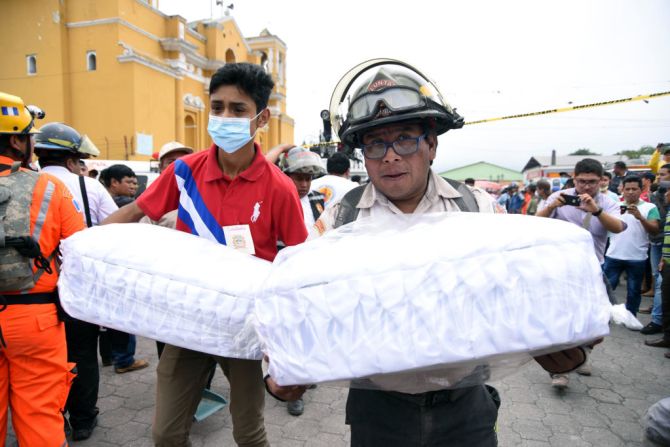 Bomberos voluntarios llevan a la morgue los ataúdes de dos niños muertos en la erupción del volcán de Fuego.