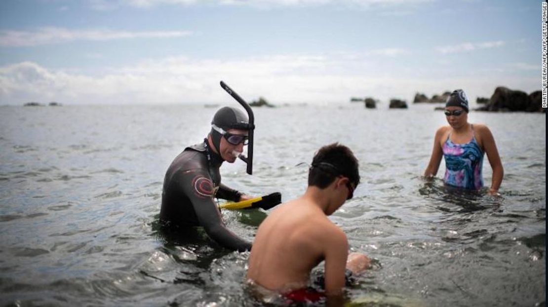 French swimmer Benoit Lecomte begins his attempt of swimming across the Pacific Ocean in Choshi, Japan on June 5, 2018, surrounded by his children.