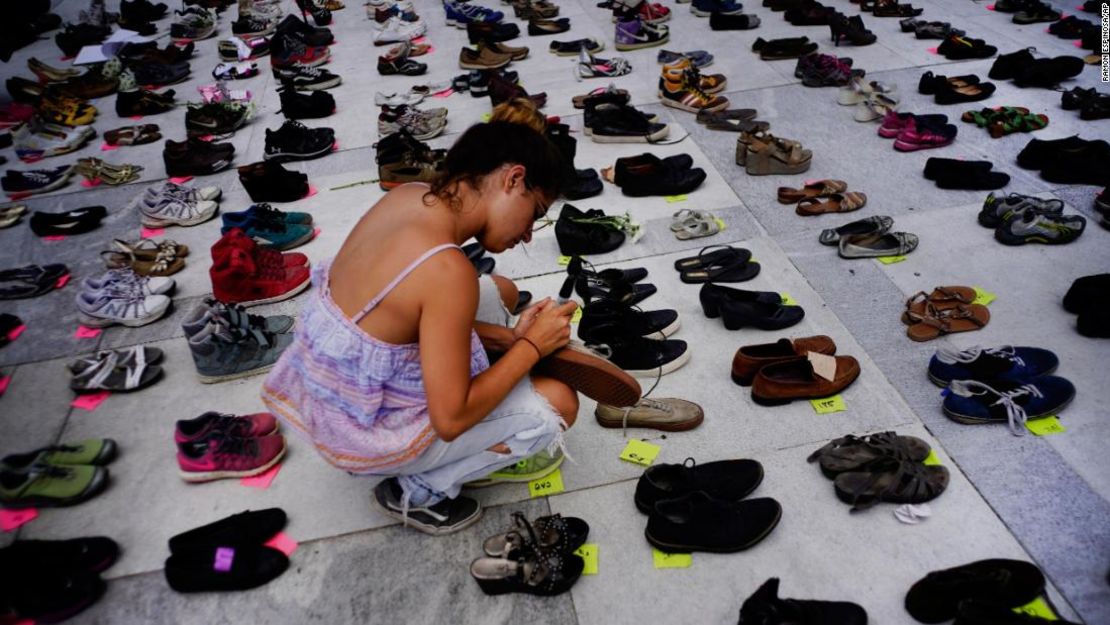 Una mujer coloca uno de los cientos de zapatos en memoria de los fallecidos por el huracán María frente al Capitolio de Puerto Rico, en San Juan, el viernes 1 de junio de 2018.