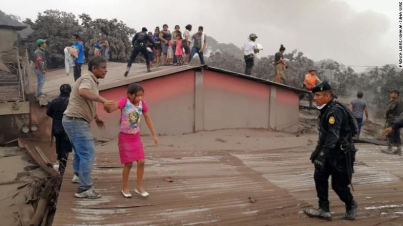 Rescatistas ayudan a una niña que evacúa una casa en Acatenango el 3 de junio.