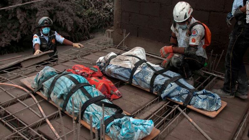 Un bombero se arrodilla junto a unos cuerpos cubiertos.