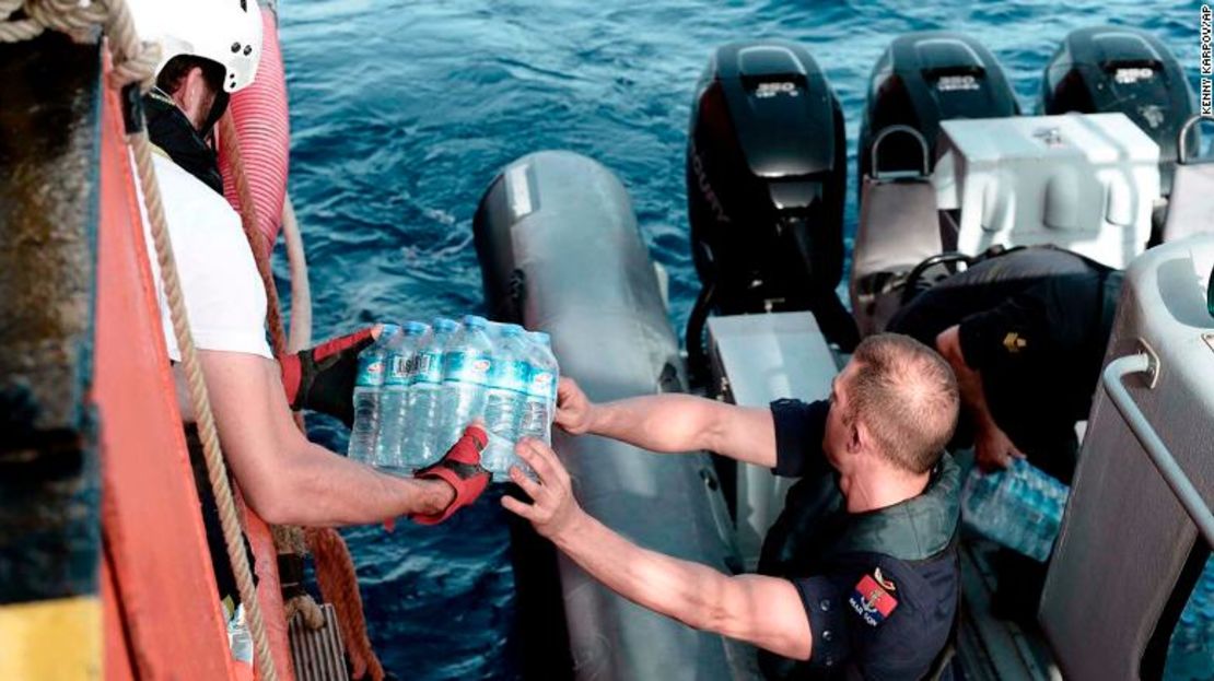 Un funcionario de la marina de Malta reparte agua al barco de rescate.